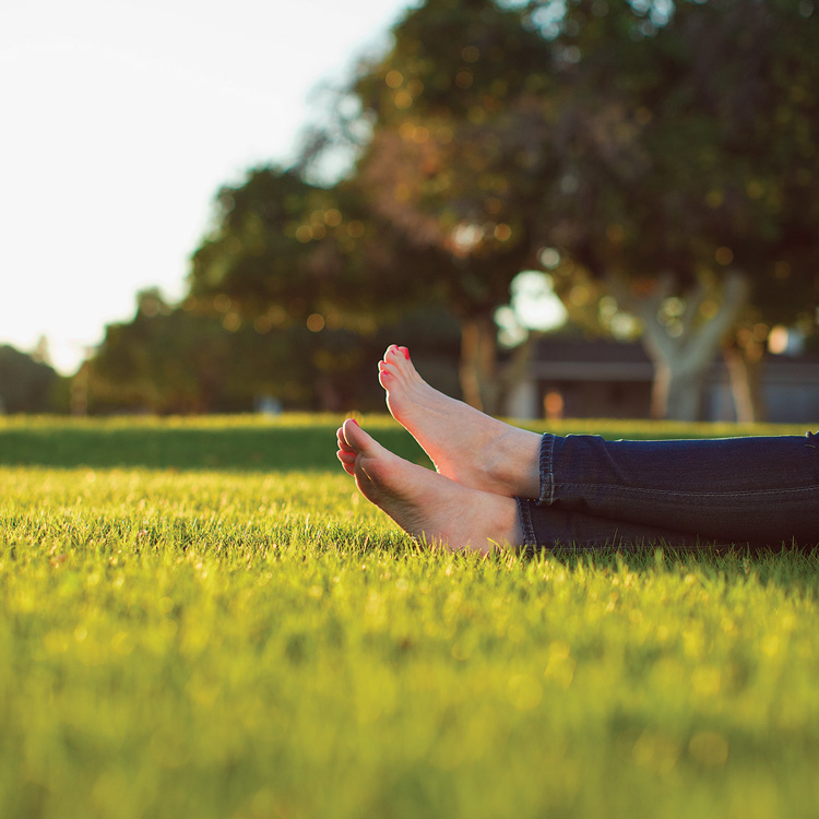 Photo of relaxed bare feet in green grass.